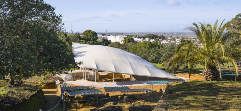 General view of the textile canopy over the tombs of Postumio and Tres Puertas with palm trees and the Carmona landscape in the background. Nd_Arquitectos. Spain. Photo by Jesús Granada.