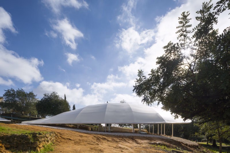 Perfil lateral de la cubierta textil emergiendo entre los árboles de la Necrópolis de Carmona como una topografía artificial. Nd_Arquitectos. España. Fotografía de Jesús Granada.