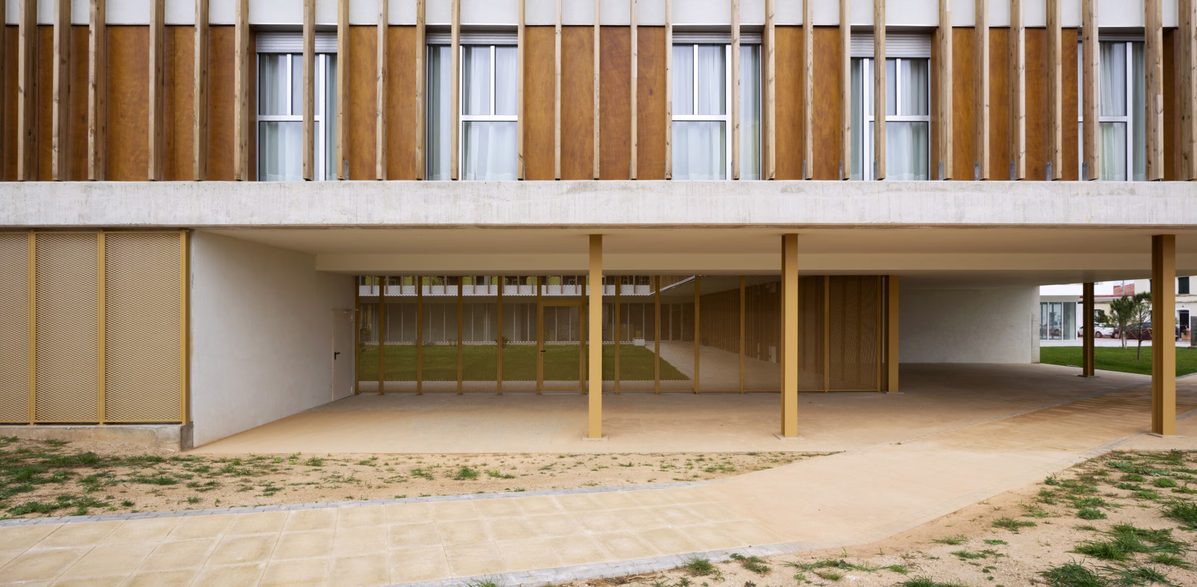 Fachada profunda ocupable revestida de lamas y paneles de madera, galería de transición entre interior y jardín. Residencia personas dependientes en Mahón, Menorca. Antonio González Liñán, SV60 Arquitectos. Fotografía de Jesús Granada