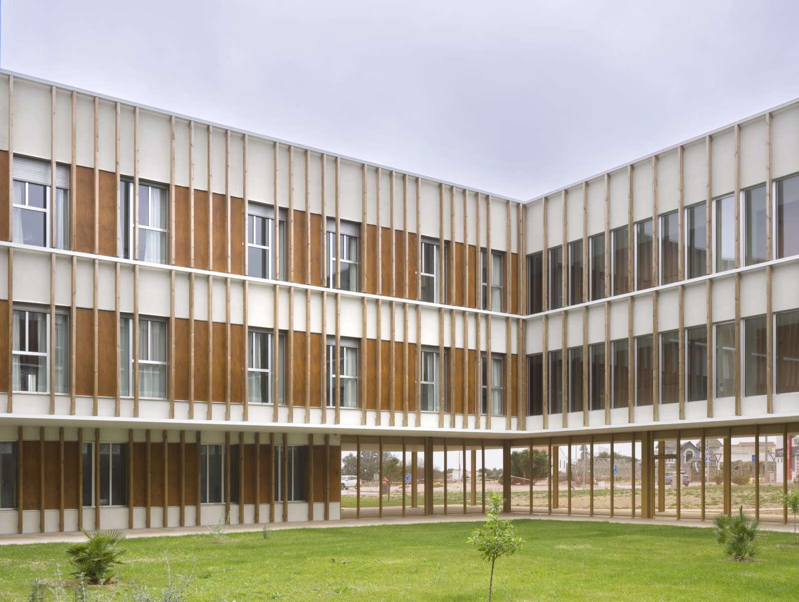 Fachada principal de la residencia con envolvente de lamas de madera y hormigón. Residencia personas dependientes en Mahón, Menorca. Antonio González Liñán, SV60 Arquitectos. Fotografía de Jesús Granada