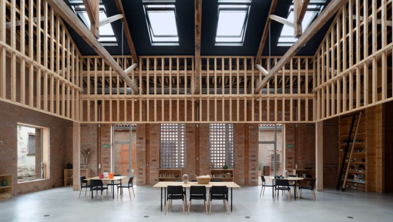 Interior de los talleres bajo las cerchas de madera reforzadas. Centro PRODIS en Terrassa, España. Harquitectes. Fotografía de Jesús Granada.